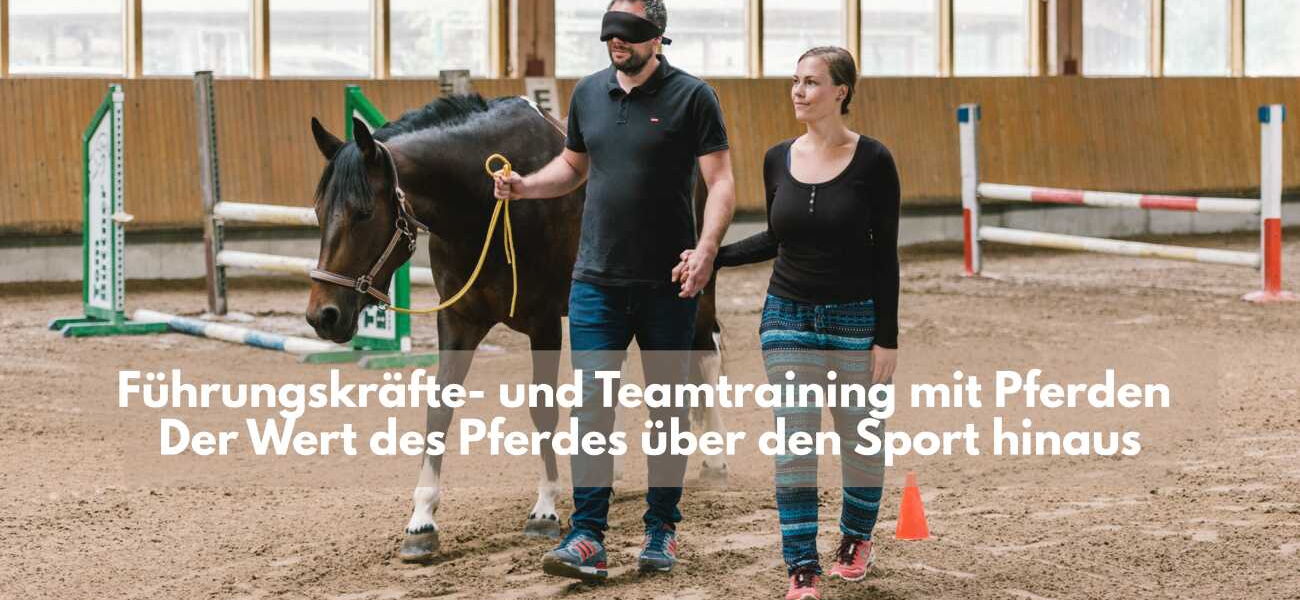 Ein Mann führt mit verbundenen Augen ein Pferd in der Reithalle und hält an der anderen Hand eine Frau